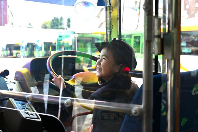 バスの運転席に座り笑顔になる参加者の様子
